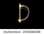 Letter D. Light painting alphabet. Long exposure photography. Drawn letter D with gold lights against black background.
