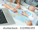 Small photo of Young man and woman in a tour agency with a travel agent choosing destination on a map