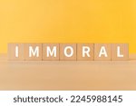 Small photo of Wooden blocks with "IMMORAL" text of concept.