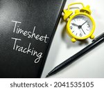 Small photo of Business concept.Text Timesheet Tracking writing on notebook with pen and clock on a white background.