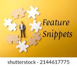 Small photo of Miniature people and white puzzle with text Feature Snippets on a yellow background.