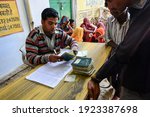 Small photo of Rajasthan, India, 24 november 2013: Ration card holders gather to collect food from a state-run ration store, shopkeeper doing entry in Ration card for record.