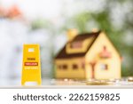 Small photo of Foreclosures and foreclosed home for sale property listings, financial concept : Yellow warning sign board with the words FORECLOSURE FOR SALE BANK-OWNED, a two-story model house, coins on a table.