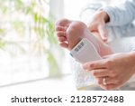 Small photo of hands of a young woman using an electrical device to soften the feet and remove calluses. body care and pedicure concept
