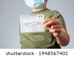 Small photo of 04-02-2021 Clarksburg, MD, USA: It is expected that kids will be getting vaccines before the start of the school year. Concept image showing a kid holding a COVID-19 vaccination record card