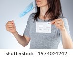 Small photo of Clarksburg, MD, USA 05-16-2021: CDC announced the lifting of face mask requirement for fully vaccinated individuals. A woman showing vaccination record card is removing her face mask and discarding it