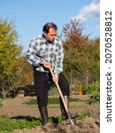 Small photo of Gardening, man digging the garden bed with spade on sunny day