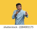 Small photo of Portrait of a young indian stand-up comedian with microphone. Isolated on yellow background.