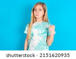 Small photo of little caucasian kid girl wearing trendy T-shirt over blue background shows fist has annoyed face expression going to revenge or threaten someone makes serious look. I will show you who is boss