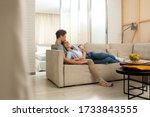 Happy woman and man resting on sofa while switching channels with remote control at home