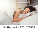 Small photo of Feeling calmness. Sleepy female keeping eyes closed while dreaming about future vacation or sleeping at the bedroom. Stock photo