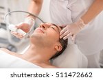 Senior man is enjoying laser rejuvenation massage at beauty salon. His eyes are closed with pleasure