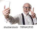 Small photo of Waist up portrait of jolly oldster making selfie and holding up two fingers. Isolated on background