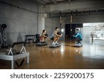 Male Instructor giving fitness class to sporty man and woman working out in dark big gym with fitness ball. Sport, training and lifestyle concept Horizontal copy-space, wide angle, full length