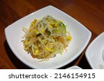 Seasoned bean sprouts are served on a white plate.