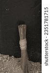 Small photo of Artistic Arrangement of Stacked Palm Broomsticks on Black Background, Discover the captivating composition of neatly piled palm broomsticks casting intricate shadows against a sleek black backdrop.