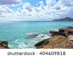 Sea waves crashing over rocks on wild stone beach in Majorca, Spain. Calm sea water, Majorca. White clouds on a blue sky over summer sea with sunlight reflection, Majorca island. Tropical sea relax