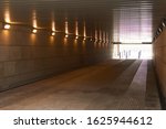 Tunnel, underpass with burning lamps and light at the end.