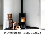 Modern black stove with burning flames and pellet bag in a living room