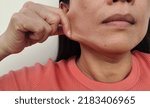 Small photo of portrait showing the fingers squeezing the flabbiness adipose sagging skin under the chin, Dullness and dark spots, problem wrinkles and flabby skin on the cheeks of the woman, concept health care.