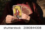 Small photo of Gorgeous female hand holds a tarot card THE MAGICIAN close-up. Willpower, creation, manifestation, illusions. Fortune teller dressed in bohemian style holds a tarot card with the sign of the magician.