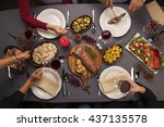 Top view of a dinner table. Roast beef, cauliflower salad, Brussels sprouts, smoked salmon, garlic bread, candle, rice, turkey & red wine. Hands holding cutlery and wine.