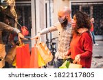 Pretty young man pointing to shop window to show clothing item his likes to his girlfriend - Beautiful young couple enjoying in shopping, having fun together, with the face mask - 