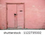 Small photo of Old pink door with combination lock on unideal peeling wall of aged building. Retro background of entrance in vintage house. Unusual imperfect rough construction. Habitable grunge glamour home.
