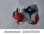 Small photo of A creepy clown is peering through a hole in the white wall. The face of a man wearing a creepy clown mask is looking at his victim through the hole. A clown madman