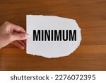 Minimum. Woman hand holds a piece of paper with the note,  minimum. Weight,  smallest, volume, number, quantity, amount, minimal and lowest.