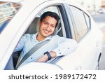 Young handsome Indian man proudly driving his own car