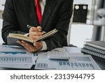 Small photo of Close up of businessman working at office with laptop, tablet and graph datasheets on his desk