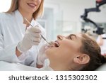 Stomatology doctor treating woman's teeth in dentistry clinic. Happy woman lying with opened mouth. Female dentist in white uniform and gloves using restoration instruments.