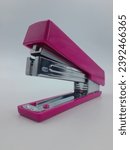 Small photo of purple stapler on a white background. Paper purple stapler on isolated white background.