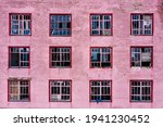 Small photo of Twelve windows with broken glass in the workshop of an old abandoned and plundered factory. Brickwork painted with pink paint