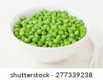 fresh cooked green peas in white bowl and a spoon