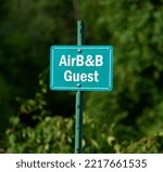 Small photo of Pelham, NH USA - July 31, 2022: A small green sign, saying AirBandB Guest, denotes the authorized parking place for a guest at an Airbnb in rural NH.