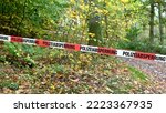 Small photo of A cordon with red and white police tape and a notice of a police cordon off an area in a forest in autumn in a German forest