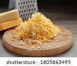 Shredded mozzarella and red cheddar cheese on wooden cutting board