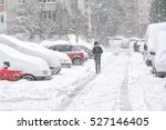 Snowstorm, snow-covered street and cars with a lonely pedestrian
