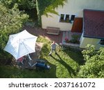 Angry man upset by flying drone over his garden. The concept of spying on neighbors and their privacy. Man trying to knock down  drone from sky over his own garden with broom. Breaking rules flying 
