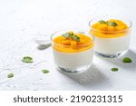 Delicious double colored mango panna cotta mousse pudding with diced mango pulp flesh topping on white table background.