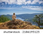 Woman sitting on the edge of the cliff and enjoying view of the valley, river and mountains. Traveling along Canada. Copy space for text, landscape composition. Travel, lifestyle concept.
