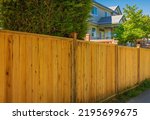 Nice new wooden fence around house. Wooden fence with lawn. Street photo, selective focus