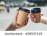 Two paper coffee cups in women's hands with perfect manicure.