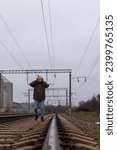 Small photo of An inattentive man walks along the rails wearing headphones. Railway danger concept