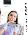 Small photo of Choice of tooth color with a special scale. Dentist select a shade of tooth enamel for the young pretty girl of the patient. Bleaching, prosthetics, orthopedic dentistry.