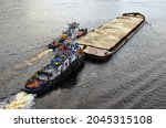 River barge loaded with sand. Landscape view of cargo ship barge loaded with sand. Top view of the barge with sand with two tugboats.