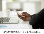 African-american businessman in suit using mobile phone in office, black man holding smartphone at workplace with laptop computer, corporate devices and apps for business concept, close up side view