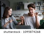 Millennial couple having fun listening to music online on computer application, smiling teenagers relaxing enjoying favorite songs dancing to new audio tracks sitting on couch at home with laptop